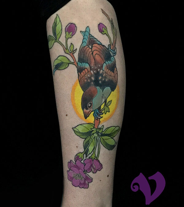 Colorful bird tattoo located on the shin.